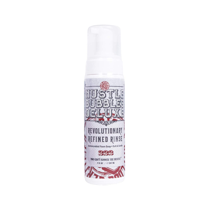 Un flacon blanc de Hustle Bubbles Deluxe - Soin nettoyant antimicrobien moussant (207ml) avec un distributeur à pompe et une étiquette décorative se tient debout sur un fond blanc uni.