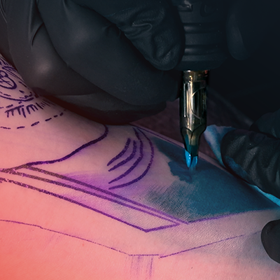 Een close-up van iemand die blauwe schaduwwerking in zijn of haar tatoeage krijgt.