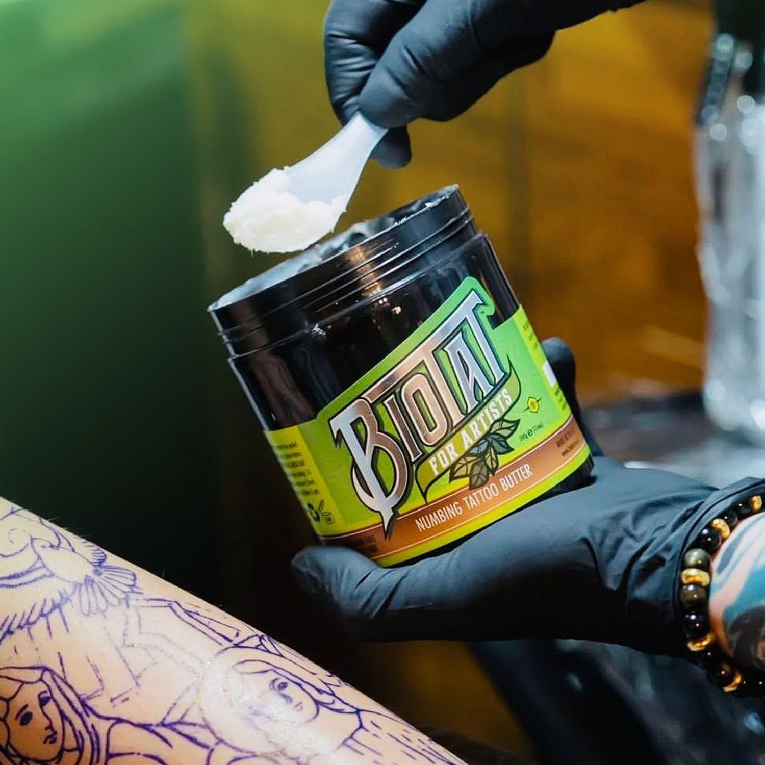 Een schepje Biotat Numbing Tattoo Butter wordt aangebracht door een tatoeëerder